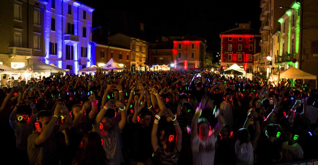 Square at night full of people wearing silent disco headphones